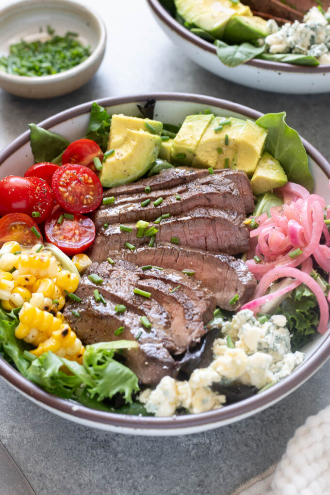 Close-up of grilled steak salad with sliced top sirloin, avocado, corn, tomatoes and blue cheese.