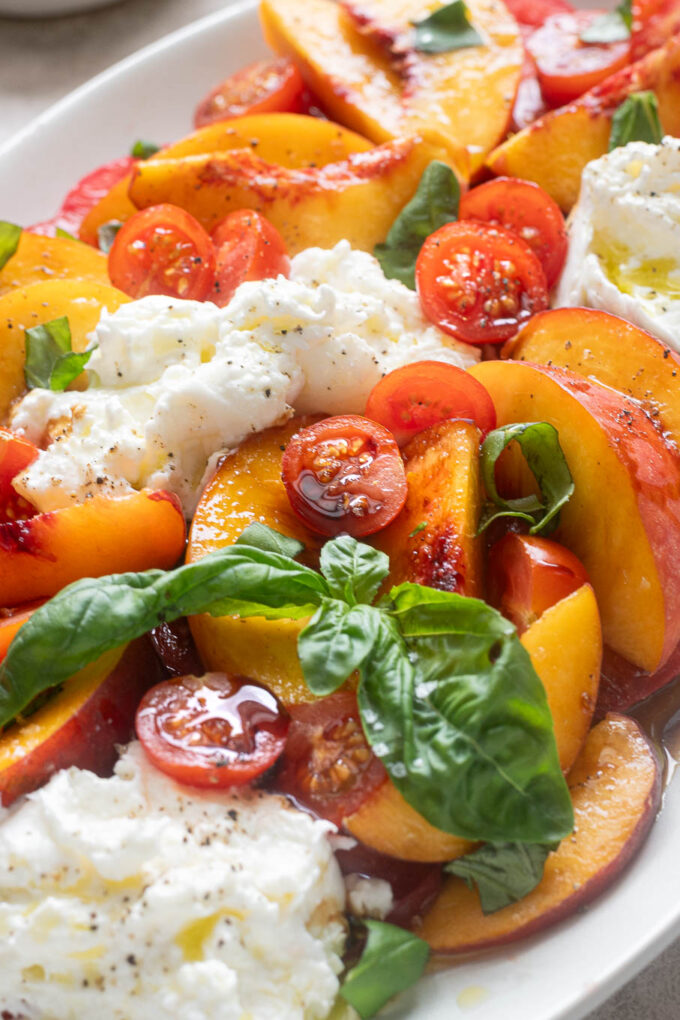 Tomato peach salad with burrata with fresh basil and balsamic glaze.
