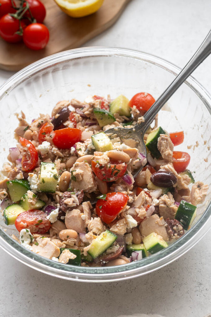 Tuna white bean salad tossed together in a glass mixing bowl.
