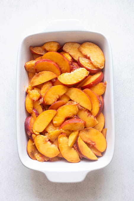 Fresh peach cobbler filling in baking dish.