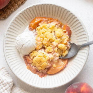 Fresh peach cobbler with shortbread cookie-style topping and vanilla ice cream.