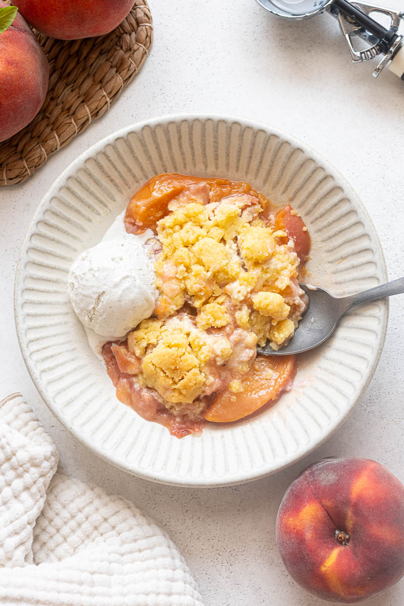 Fresh peach cobbler with shortbread cookie-style topping and vanilla ice cream.
