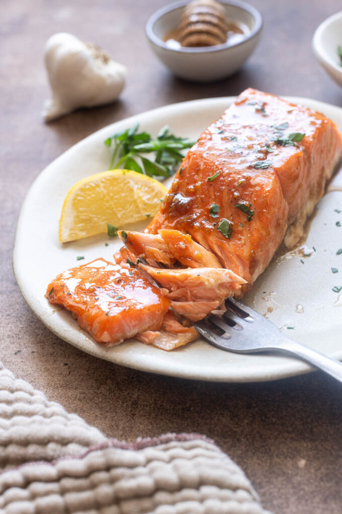Forkful of honey garlic salmon on a plate.