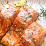 Honey garlic salmon on a platter with parsley and lemon.
