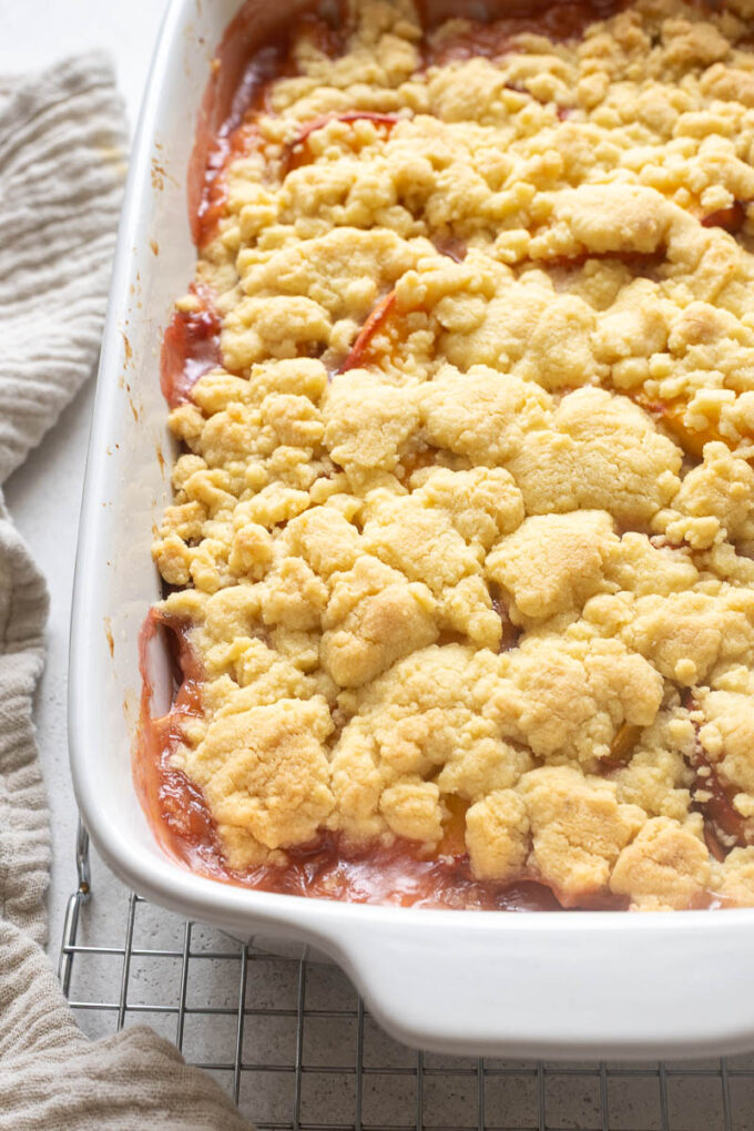 Peach cobbler with cookie topping in baking dish.