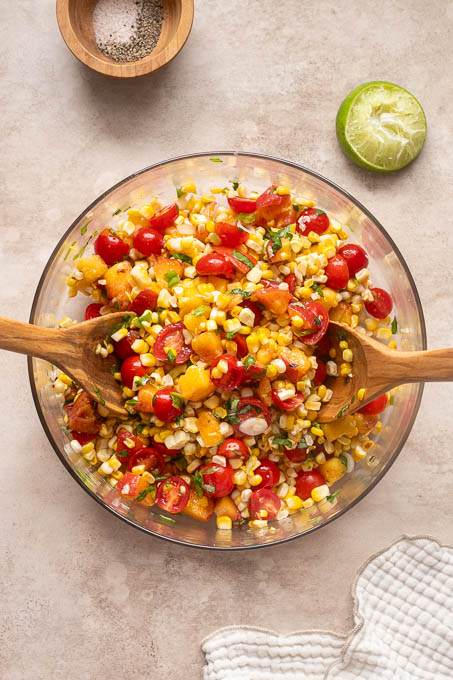Ingredients for peach tomato corn salad combined in a bowl.