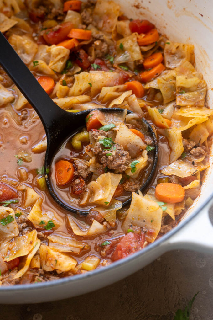 Ladle filled with cabbage soup with ground beef.