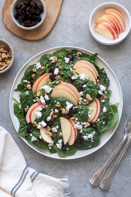 Assembled spinach and apple salad on a plate without dressing.