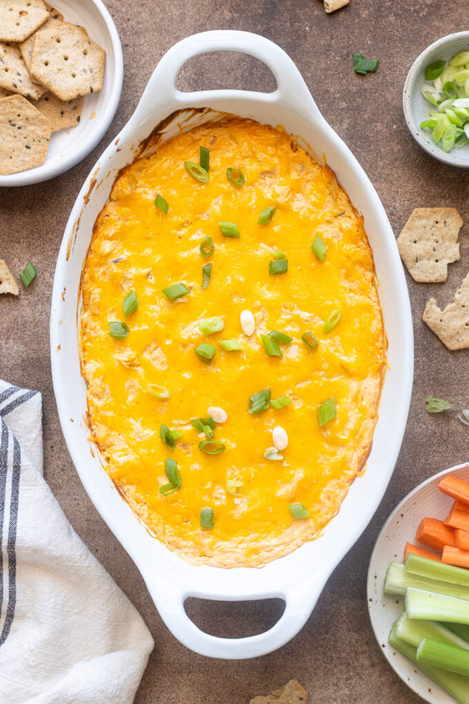 Baked buffalo chicken dip with Greek yogurt, melted cheddar, and green onions in baking dish.