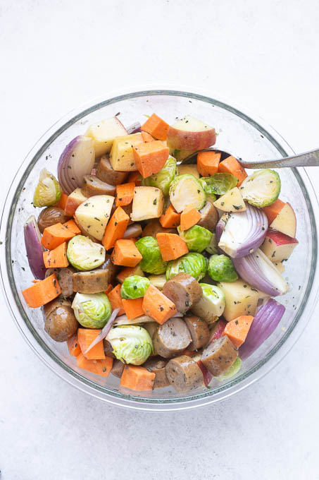 Sausage and fall vegetables tossed with maple dijon dressing in bowl.