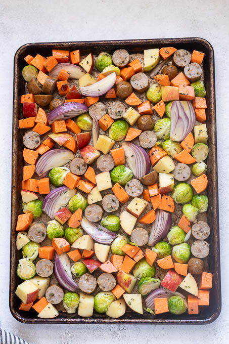 chicken apple sausage and fall veggies in single layer on sheet pan.