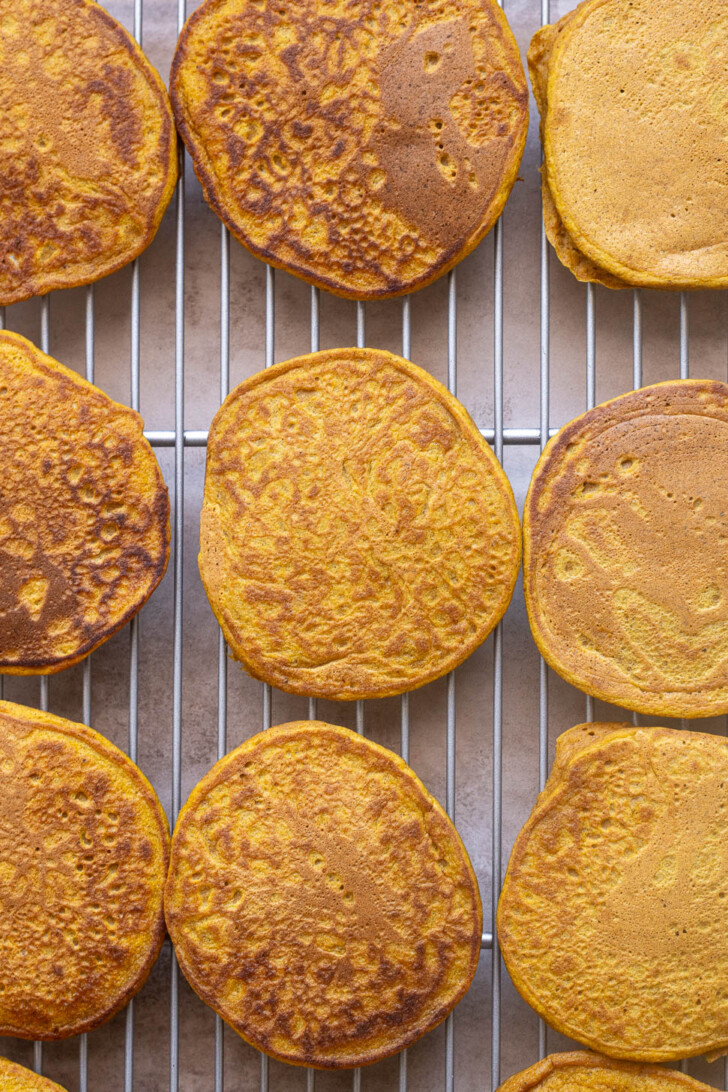 Pumpkin oat flour pancakes on wire rack.
